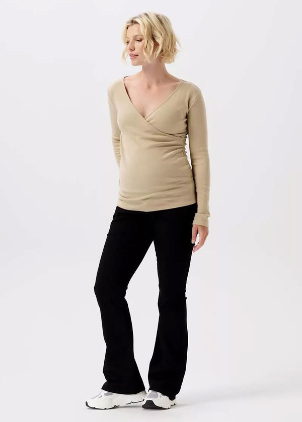 Eine schwangere Frau trägt eine schwarze Umstandshose aus Baumwolle mit ausgestelltem Bein.