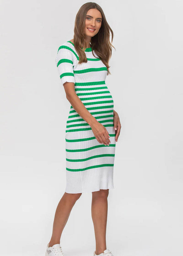 Junge schwangere Frau trägt engangliegendes Strickkleid in Weiss mit grünen Streifen.