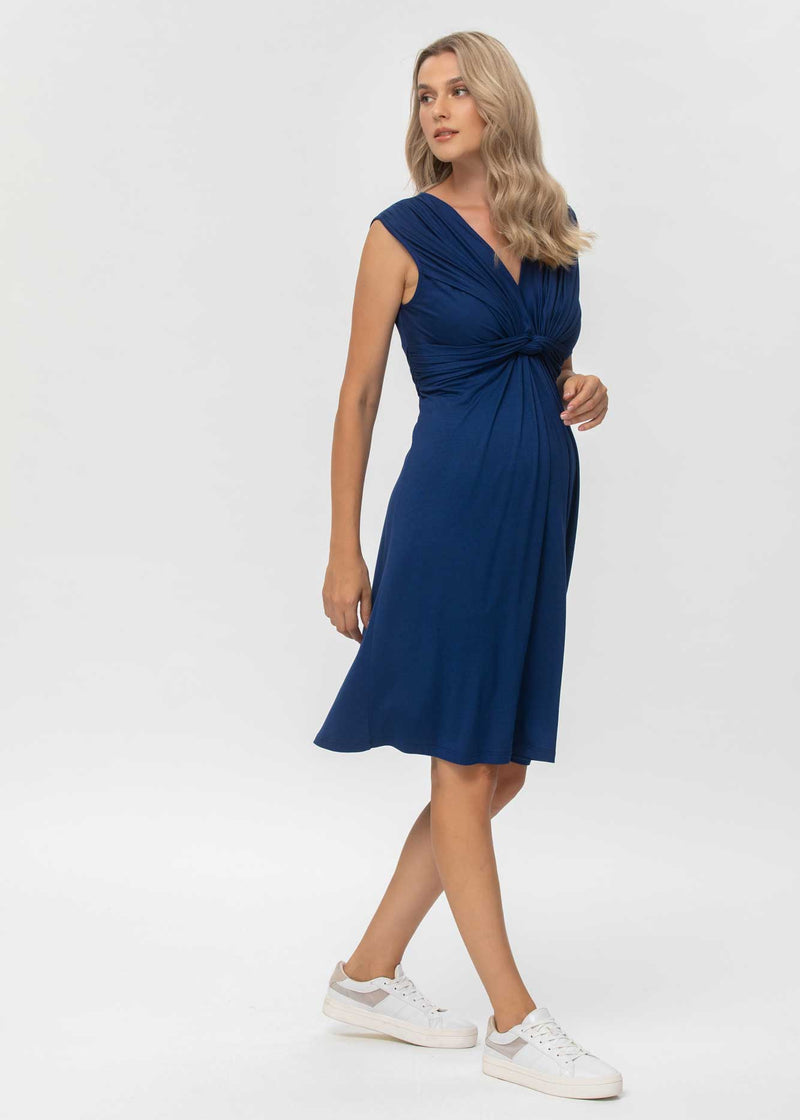 Schwangere Frau trägt blaues, ärmelloseses Jerseykleid in Wickeloptik. Das Kleid eignet sich dank der versteckten Stillfunktion sehr gut zum Stillen.