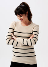 Schwangere Frau trägt beigefarbenen Umstands-Strickpullover mit kleinen Puffärmeln und schwarzen Streifen.