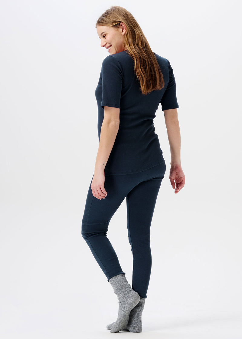 Schwangere Frau trägt kurzärmeliges Shirt in Dunkelblau. Das Shirt hat vorne Knöpfe, welche das Stillen erleichtern.