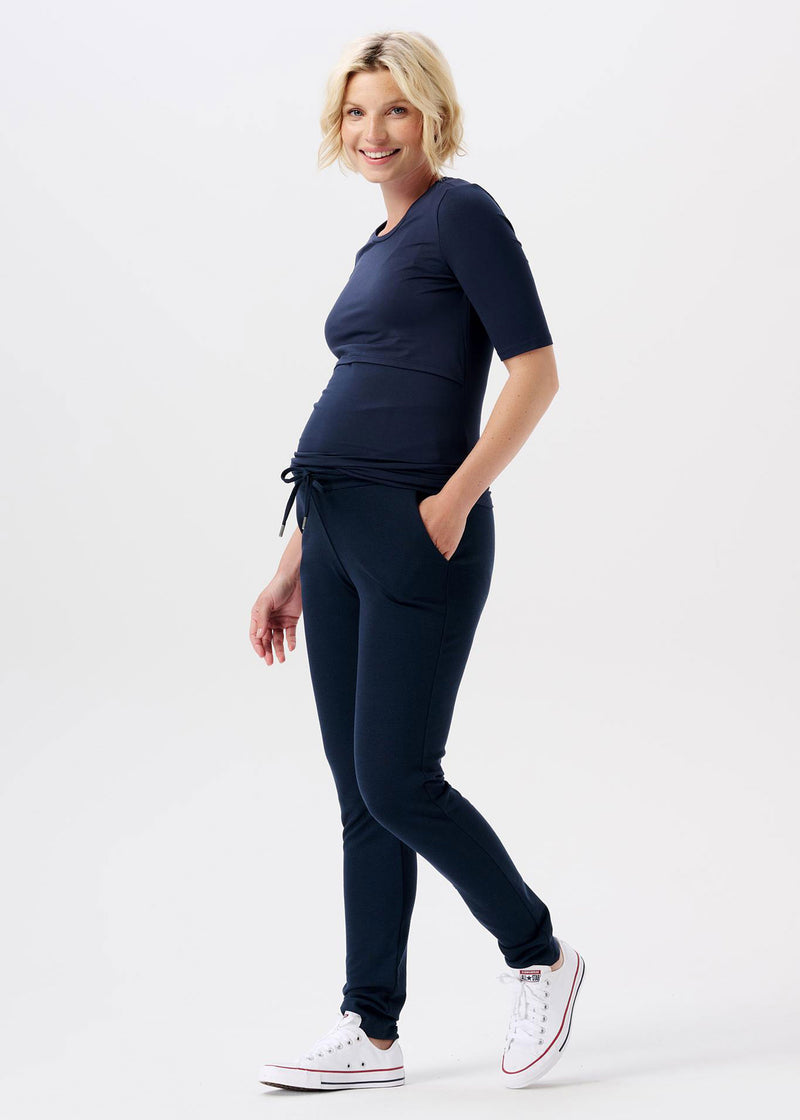 Schwangere Frau trägt dunkelblaue Umstandshose mit Kordelzug aus dickem Jerseystoff.