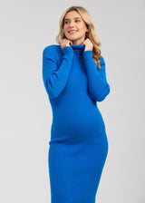 Schwangere Frau trägt enganliegendes Umstands-Strickkleid in Blau. Das Schwangerschaftskleid ist knielang und betont den Babybauch