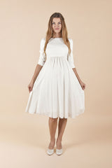 Model trägt Umstands-Hochzeitskleid Beverly in Weiss mit 3/4-Ärmeln.