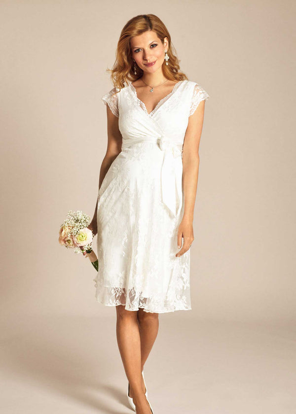 Schwangere Frau trägt das Umstands-Hochzeitskleid EDEN in der kurzen Version von Tiffany Rose. Das Kleid hat einen CacheCoeur-Ausschnitt und ist aus Spitze.