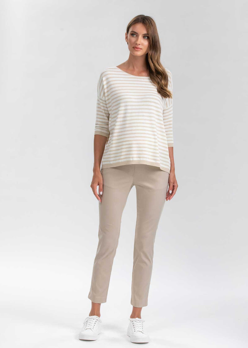 Schwangere Frau trägt beige, eng geschnittene Umstands-Business-Hosen in 7/8-Länge.