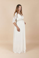 Seitenansicht des Umstands-Hochzeitskleids Cecilia (lang) in Off-White. Das Kleid hat ein elastisches Spitzenoberteil mit V-Ausschnitt und 3/4-Ärmeln sowie einen lang fliessenden Rock, der dem Babybauch angenehm Platz gibt – ideal für Ziviltrauung/Standesamt. Hinweis: Schärpe nicht enthalten (separat erhältlich).