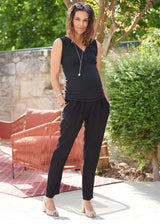 Schwangere Frau trägt eine elegante, schwarze Schwangerschaftshose aus Crêpe mit Jerseybund, Vorderansicht, in Gartenumgebung