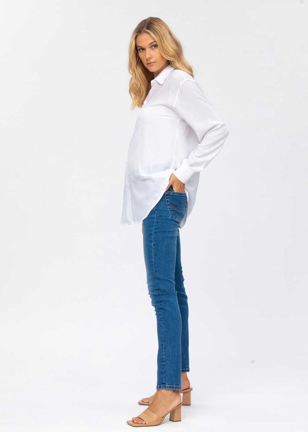 Schwangere Frau trägt eng anliegende Umstands-Jeans. In Ligth Wash