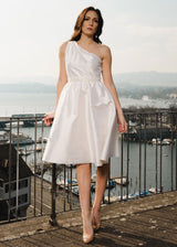 Frau trägt elegantes One-Shoulder-Kleid aus ecrufarbener Wildseide. Im Hintergrund sieht man den Zürichsee. Das Kleid eignet sich für die Ziviltrauung.