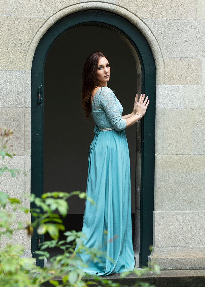 Frau trägt festliches bodenlanges Seidenkleid in Aqua mit Spitzenoberteil und Dreiviertel-Ärmeln