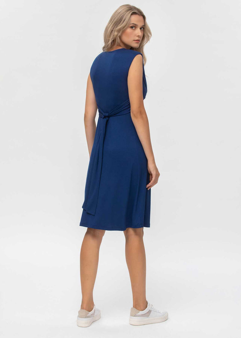 Schwangere Frau trägt blaues, ärmelloseses Jerseykleid in Wickeloptik. Das Kleid eignet sich dank der versteckten Stillfunktion sehr gut zum Stillen.