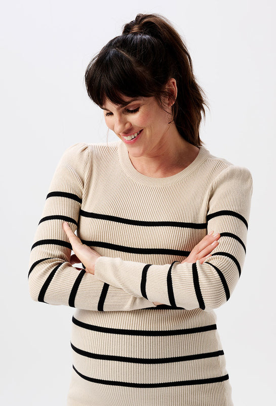 Schwangere Frau trägt einen Umstands-Pullover in beige mit schwarzen Streifen. Der Pullover hat lange Puffärmel.